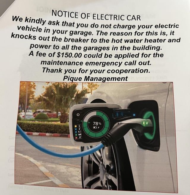 Skilt med forbud mod opladning af elbiler i en garage grundet overbelastning.